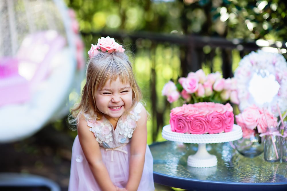 little girl with pink cake at party