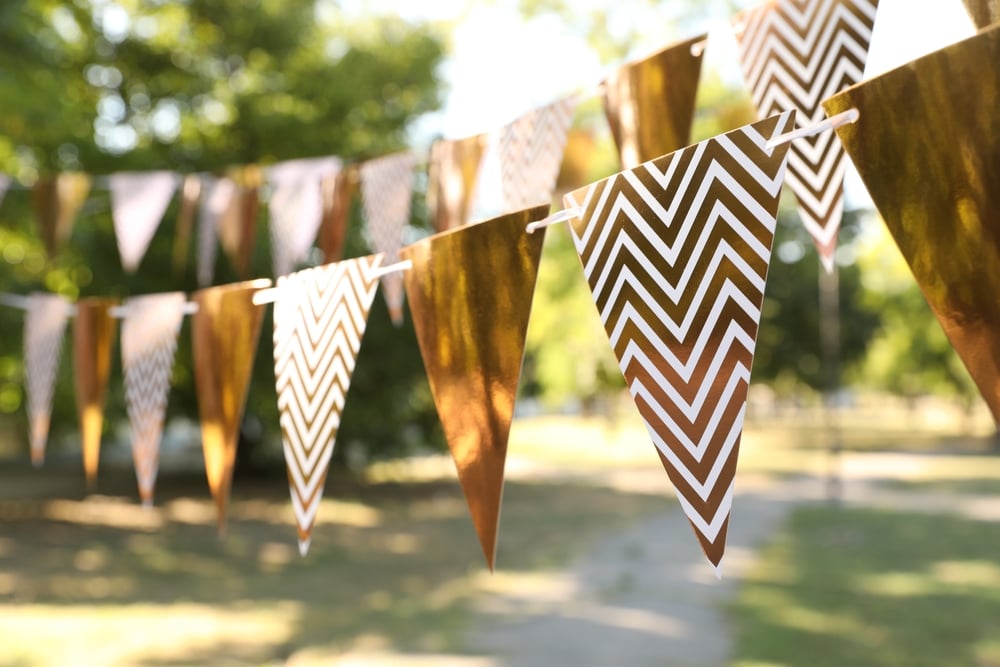 Golden bunting hanging outside over grass