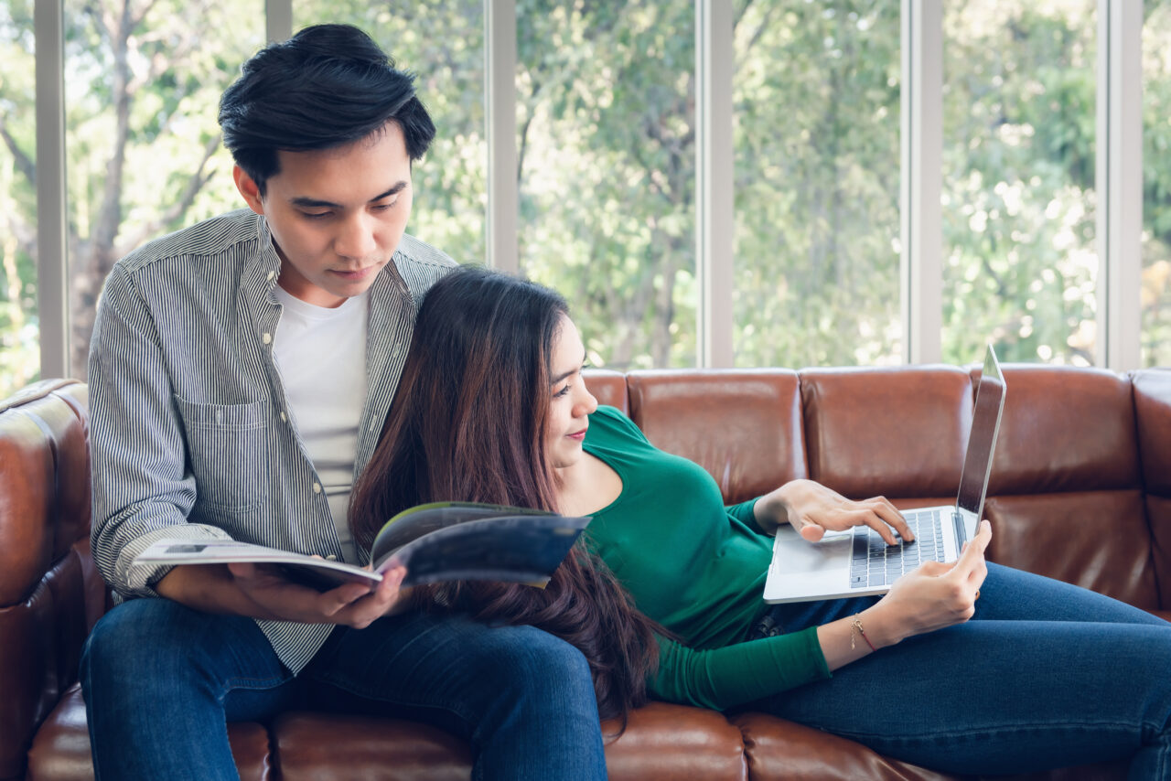 Couple having comfortable moments in Living Room Reading Magazine and Working on computer.