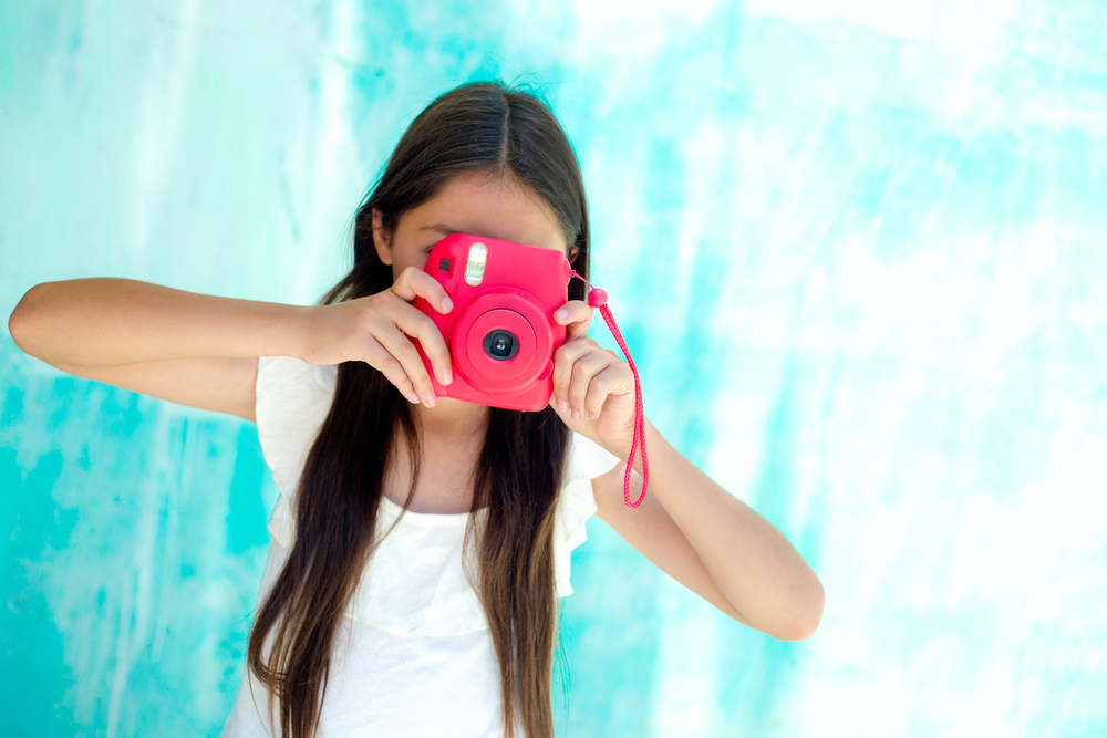 Teen girl holds bright red camera up