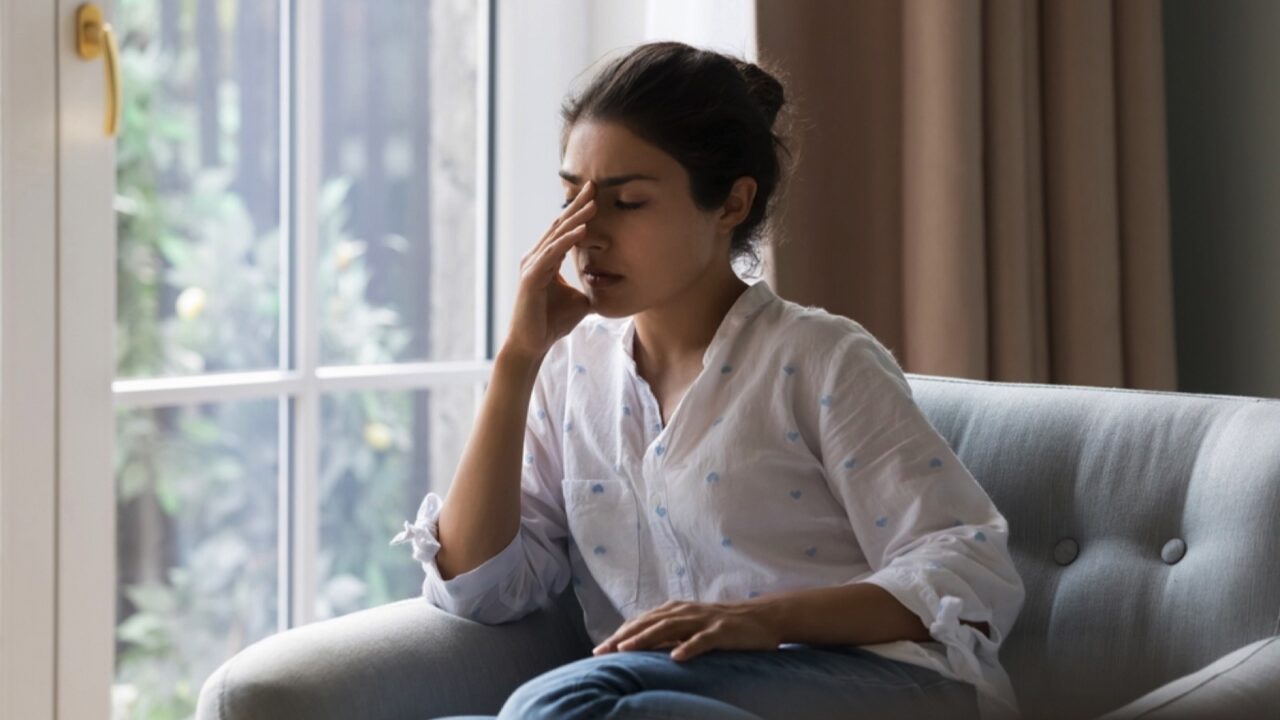 Woman sitting by a window depressed and sad.