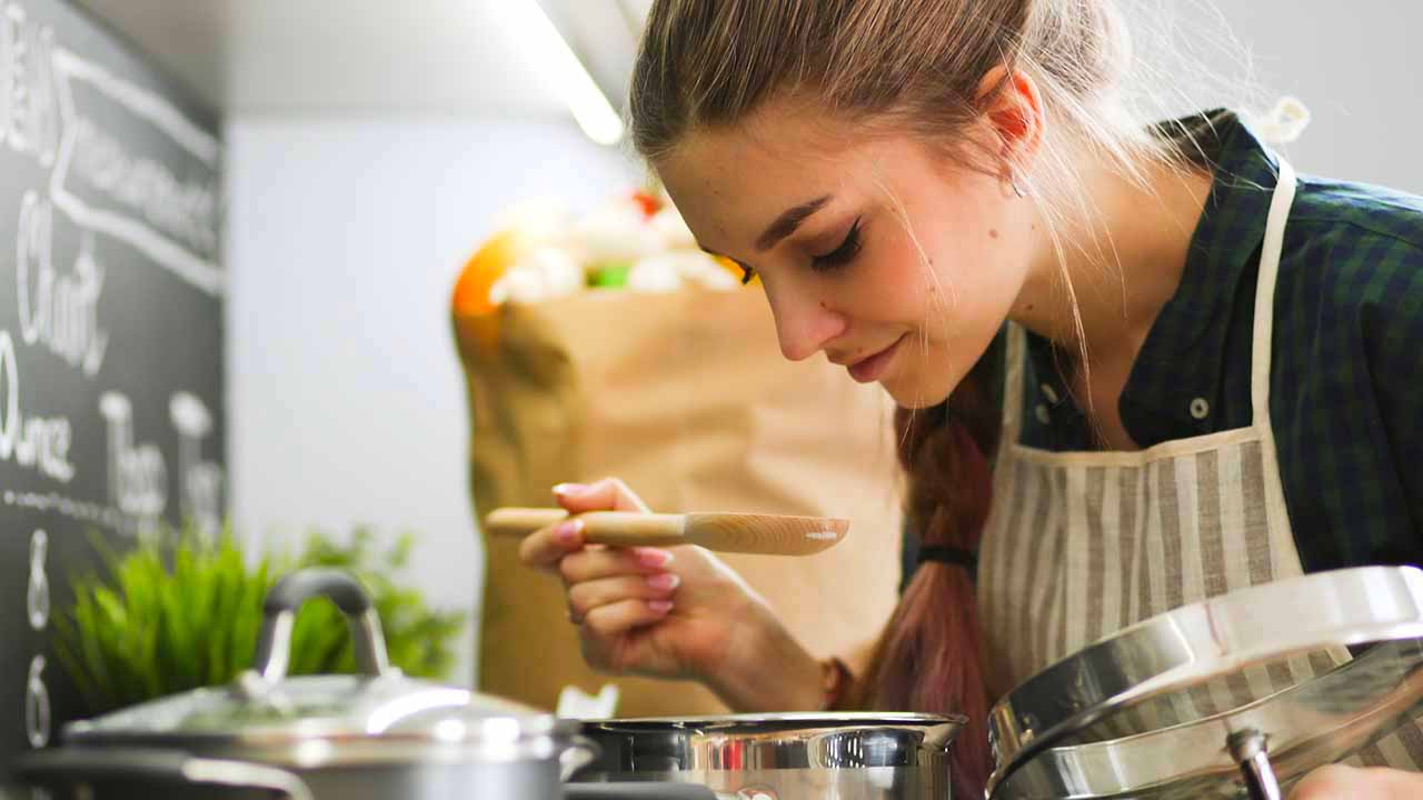 woman checking the flavor of food as she cooks in the kitchen.