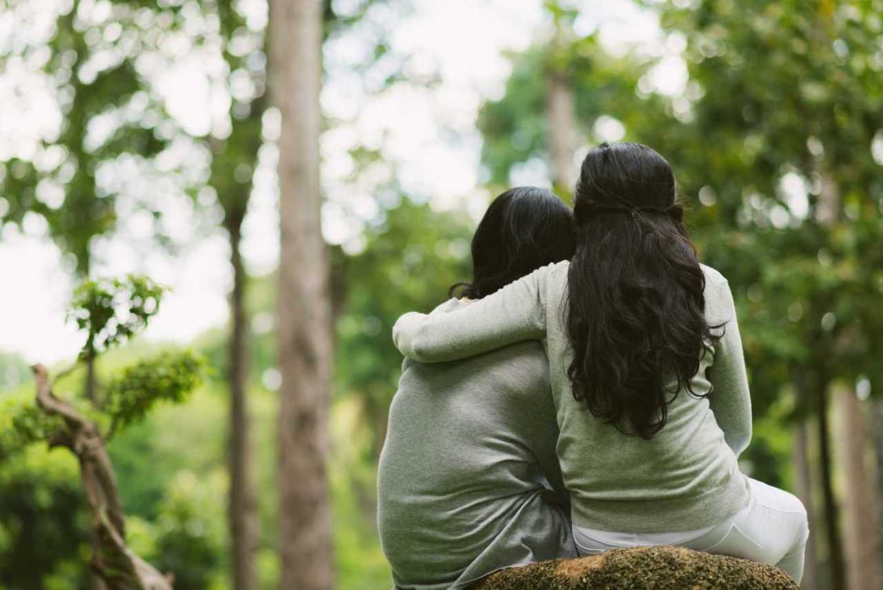 Friends forever. Friends sit in nature one friend comforts the other with a hug.