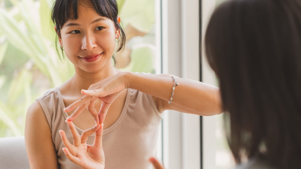 Woman uses sign language with friend.