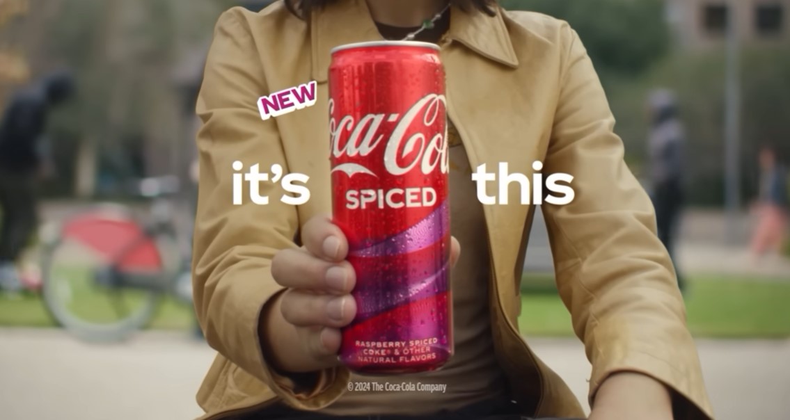 A woman holds up a can of Coca-cola spiced.