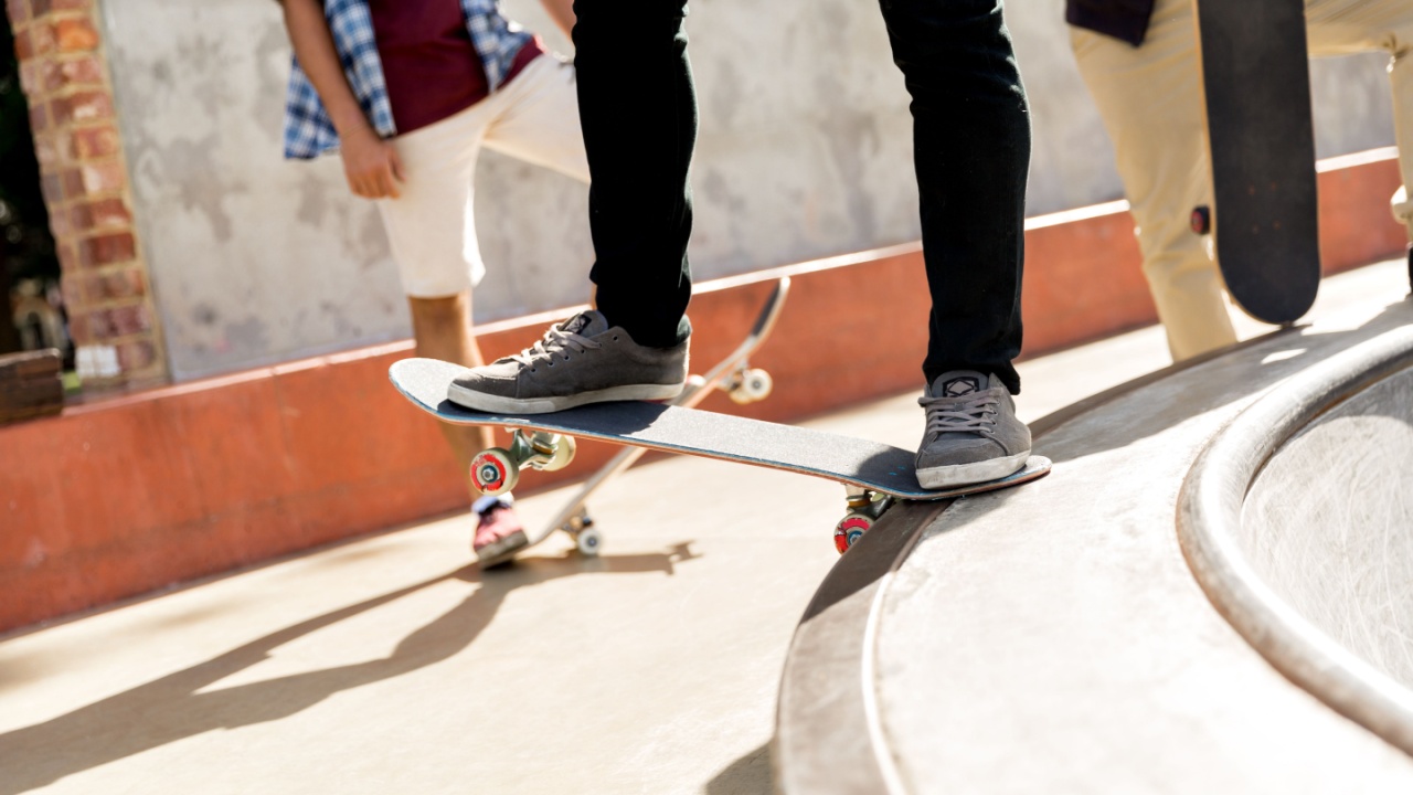 Teen's feet standing on skateboard about to move.