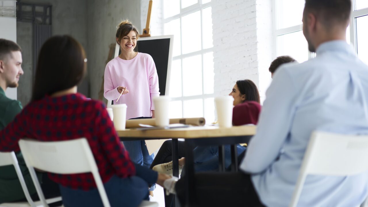 Woman smiles as she gives a presentation at work.