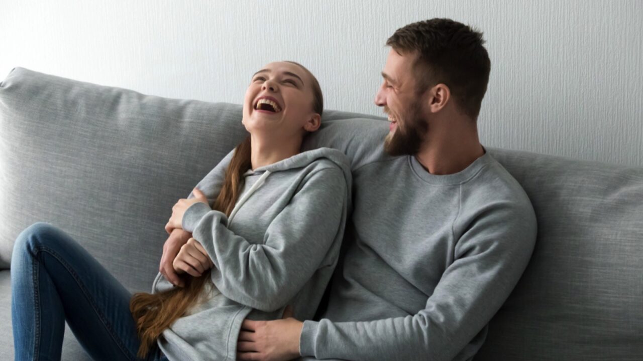 Couple joking together on the couch.