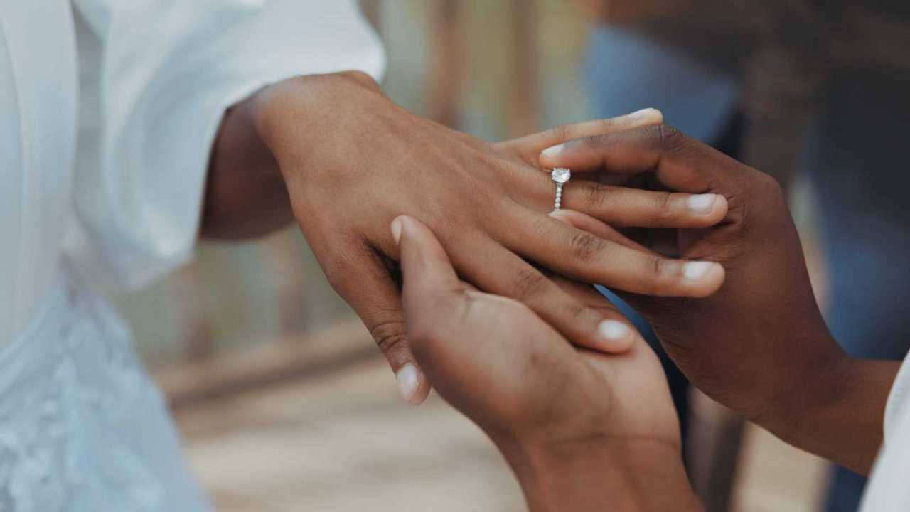 a person putting a ring on a finger.